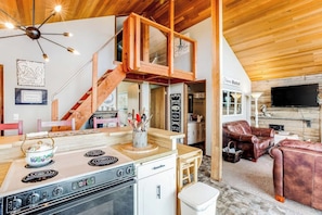 A kitchen with a stove, a wooden staircase, and a dining area with a table and chairs. - 3BR Oceanfront Dog Friendly - Deck (Ocean Shores)