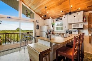 A kitchen with a wooden ceiling, white cabinets, a central island, and a view of the outdoors. - 3BR Oceanfront Dog Friendly - Deck (Ocean Shores)