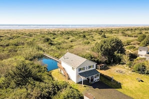 A single-story house with a pool, surrounded by dense shrubbery and a view of the ocean. - 3BR Oceanfront Dog Friendly - Deck (Ocean Shores)