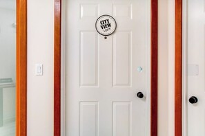 A white door with a 'CITY VIEW LOFT' sign, a keyhole, and two black door handles.