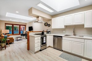 A modern kitchen with white cabinetry, a built-in oven, and a dishwasher.