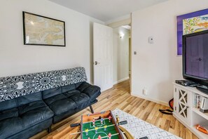 A living room with a sofa, a foosball table, a television, and a map on the wall. - 2BR Dog Friendly - Dock - Deck - Foosball - Washer Dryer (Westport)