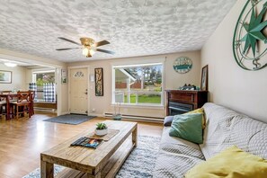 A living room with a wooden coffee table, a sofa, a ceiling fan, and a large window. - 2BR Dog Friendly - Dock - Deck - Foosball - Washer Dryer (Westport)