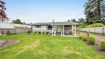 A single-story house with a front porch, a fenced yard, and a small garden area.