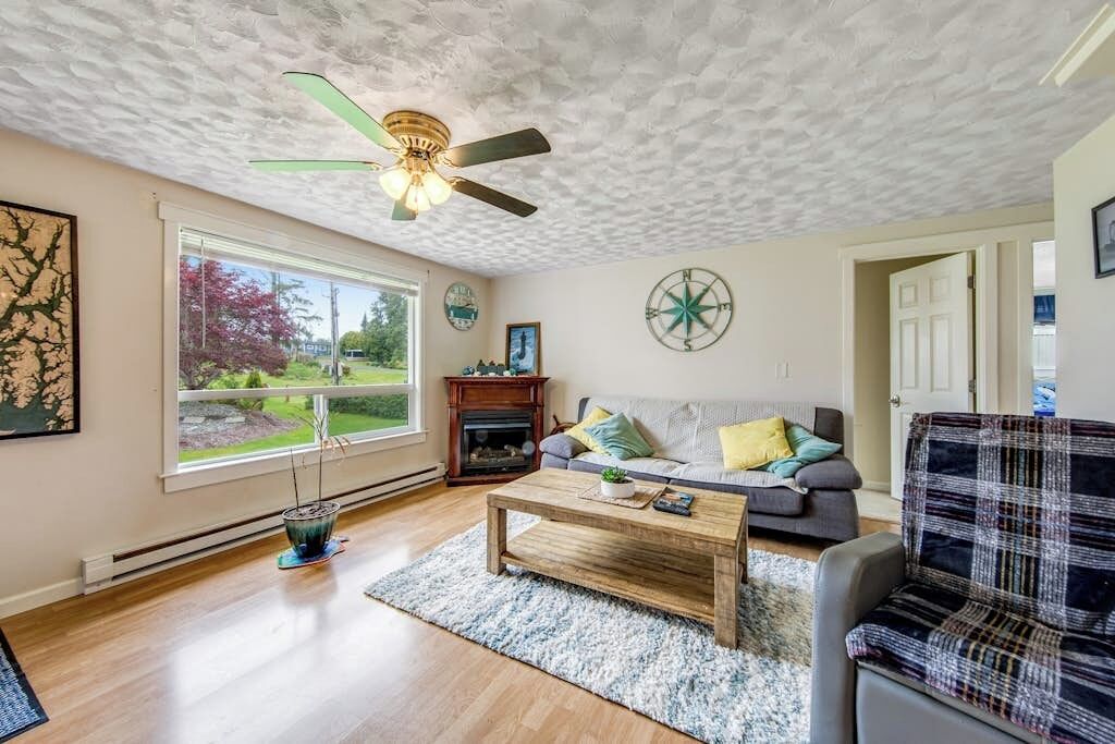 Een woonkamer met een plafondventilator, een open haard, een bank en een salontafel.