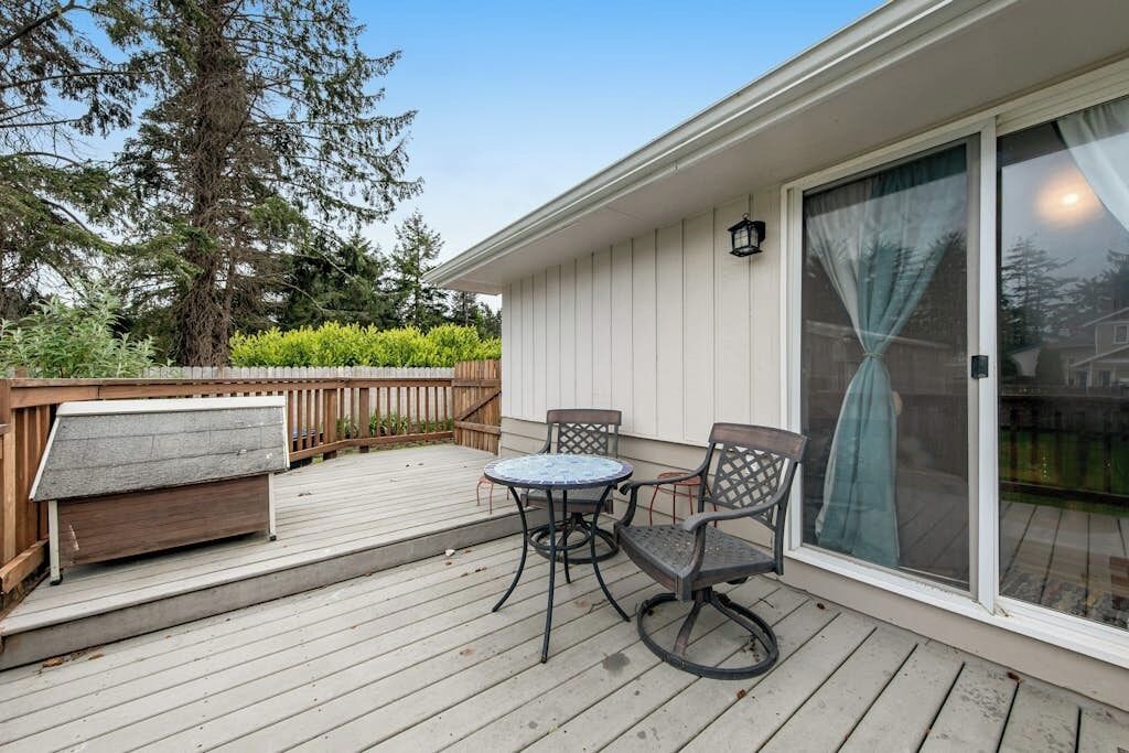 A covered patio with a table and chairs, a bench, and a sliding glass door.
