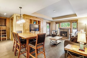 A spacious living area with a fireplace, a dining table with chairs, and a television.