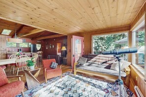 A cabin interior with a dining area, a sofa, and a telescope. - 1BR Soundview House - Fireplace (Gig Harbor)