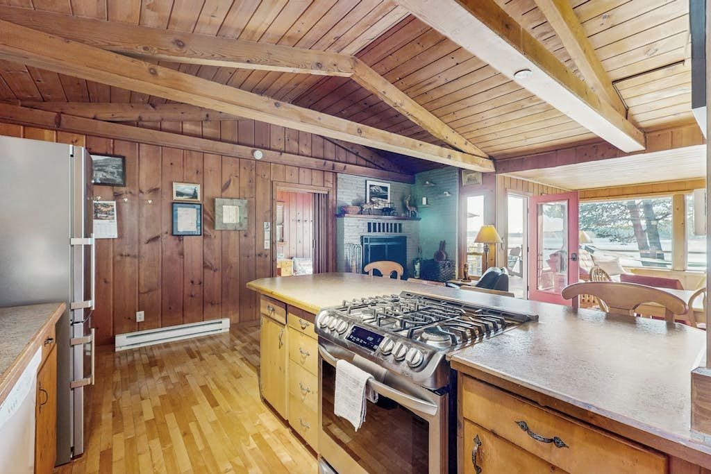 A kitchen with wooden walls, a gas stove, and a refrigerator.