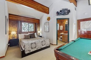 Een slaapkamer met een bed, een pooltafel en een badkamer die door een geopende deur zichtbaar is.