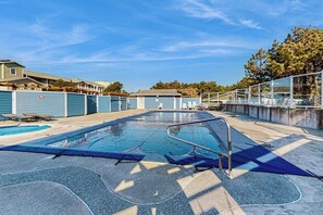 Ein Schwimmbecken mit Sprungbrett, umgeben von einem Zaun und einer überdachten Fläche.