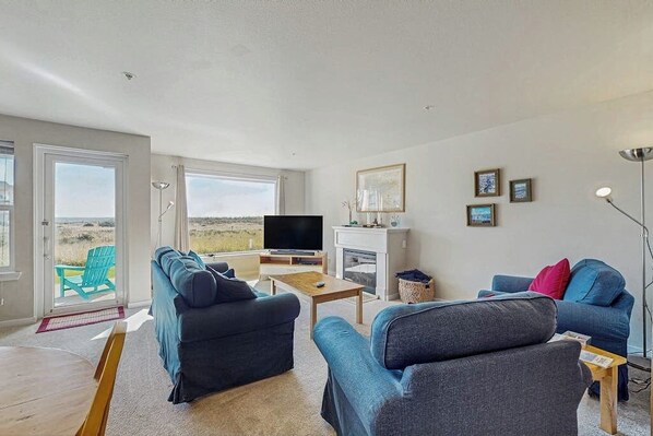 Ein Wohnzimmer mit Fernseher, zwei Sofas, einem Couchtisch und einem Kamin.