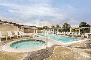 Ein Pool mit Liegestühlen und einer kleinen Whirlwanne, umgeben von einer Sonnenterrasse.