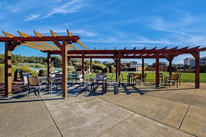 Ein Patio im Freien mit Tischen und Stühlen unter einer hölzernen Pergola.