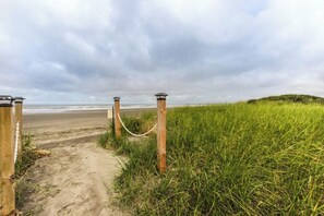 Um caminho que leva a uma praia, com uma barreira e postes de luz.