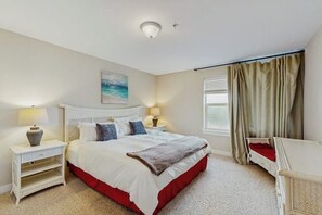 Ein Schlafzimmer mit Bett, Nachttischen, einem Fenster mit Vorhängen und einem Bild an der Wand.