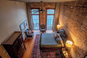 Ein Zimmer mit Bett, Schreibtisch, Stuhl und Meerblick durch große Fenster.