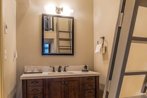 A bathroom with a large mirror, a sink with two faucets, and a towel rack. - Studio Room w/ Water Views overlooking The Bay (Port Townsend)