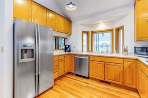 A modern kitchen with wooden cabinets, stainless steel appliances, and a dishwasher. - 4BR Bayview Dog Friendly - Deck - Garage Parking (Port Ludlow)
