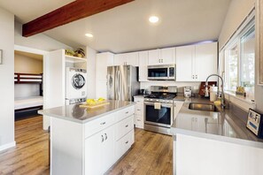 Une cuisine moderne avec des meubles blancs, des appareils en acier inoxydable et un îlot central.