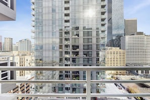 A high-rise building with a modern glass facade, multiple balconies, and a view of the cityscape. - 1BR condo near attractions with pool & hot tub (Seattle)