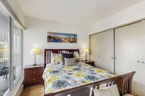 A bedroom with a bed, bedside tables, a wardrobe, a window, and a painting on the wall. - 1BR condo near attractions with pool & hot tub (Seattle)