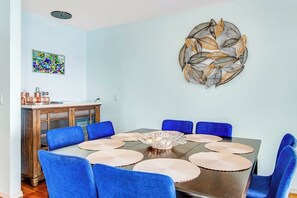 A dining area with a round table, blue chairs, and a decorative wall piece.