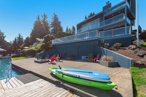 A modern building with a pool, outdoor seating, and a kayak.