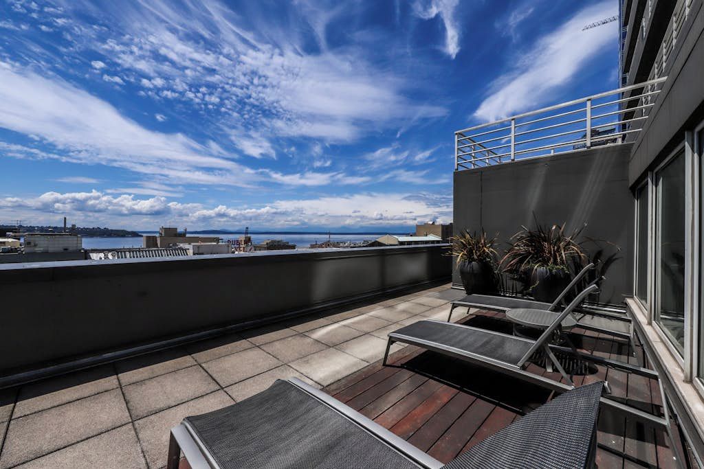 Eine Dachterrasse mit Meerblick, einer Geländer und Gartenmöbeln.