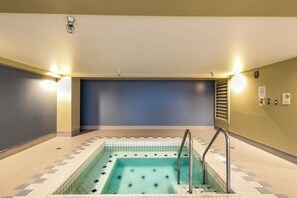 A swimming pool with a tiled floor, a metal ladder, and wall-mounted lights. - 2 BR downtown condo with amazing views & pool (Seattle)
