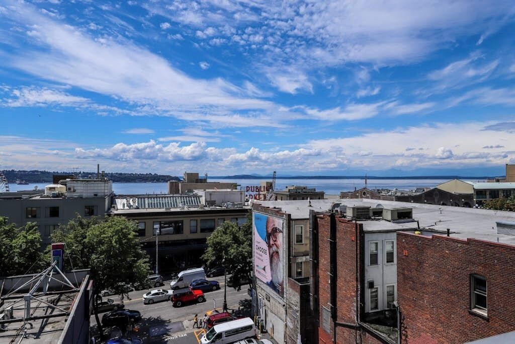 Une vue sur la ville, avec des immeubles, un parking et un plan d’eau en arrière-plan.