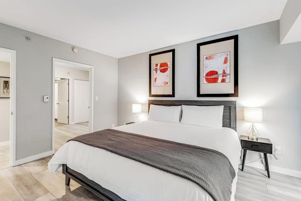 A modern bedroom with a large bed, two bedside tables, and artwork on the wall.