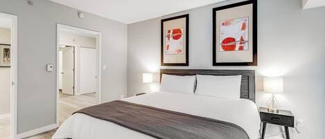A modern bedroom with a large bed, two bedside tables, and artwork on the wall.