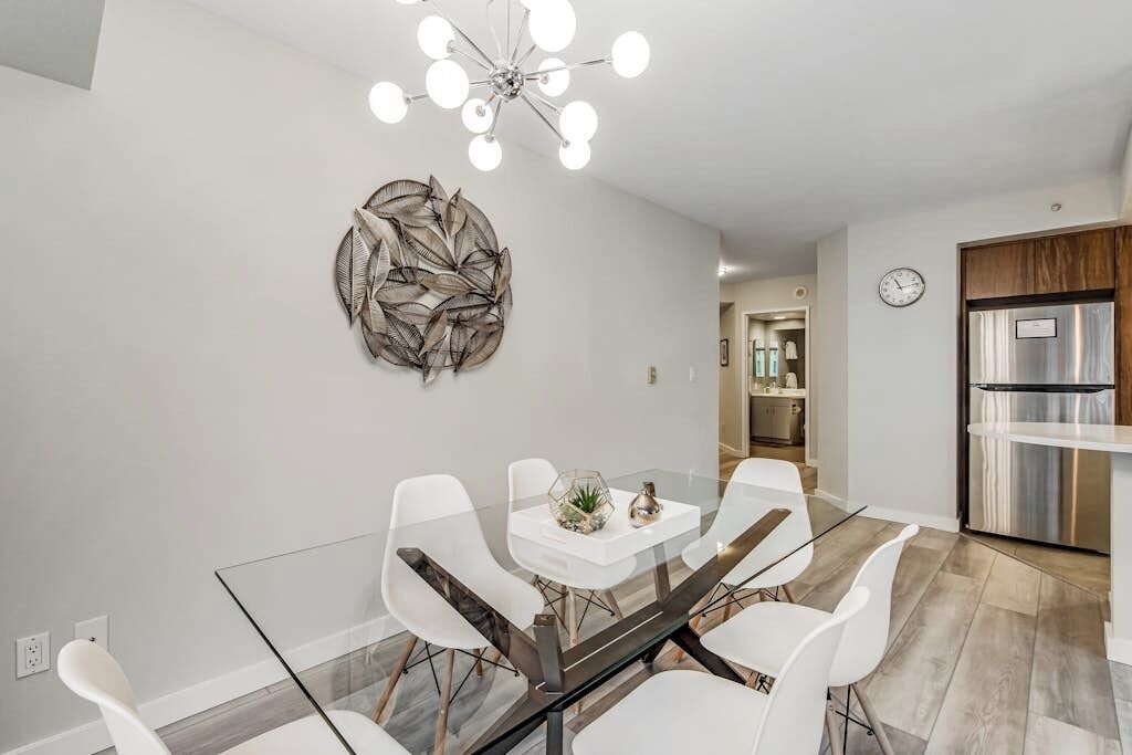 Un comedor moderno con una mesa de vidrio, sillas blancas y un adorno en la pared.