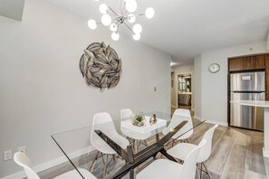 A modern dining area with a glass table, white chairs, and a decorative wall piece. - 2 BR downtown condo with amazing views & pool (Seattle)