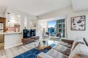 A modern living room with a large flat-screen TV, a glass coffee table, and a sofa. - 2 BR downtown condo with amazing views & pool (Seattle)