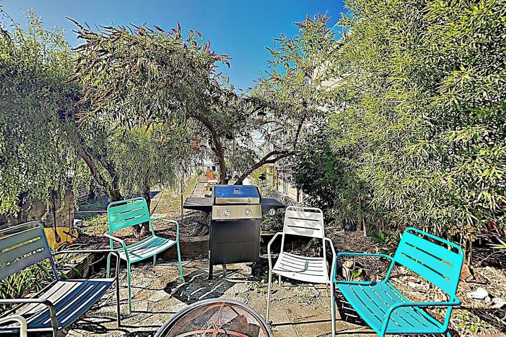 An outdoor seating area with metal chairs and a barbecue grill.