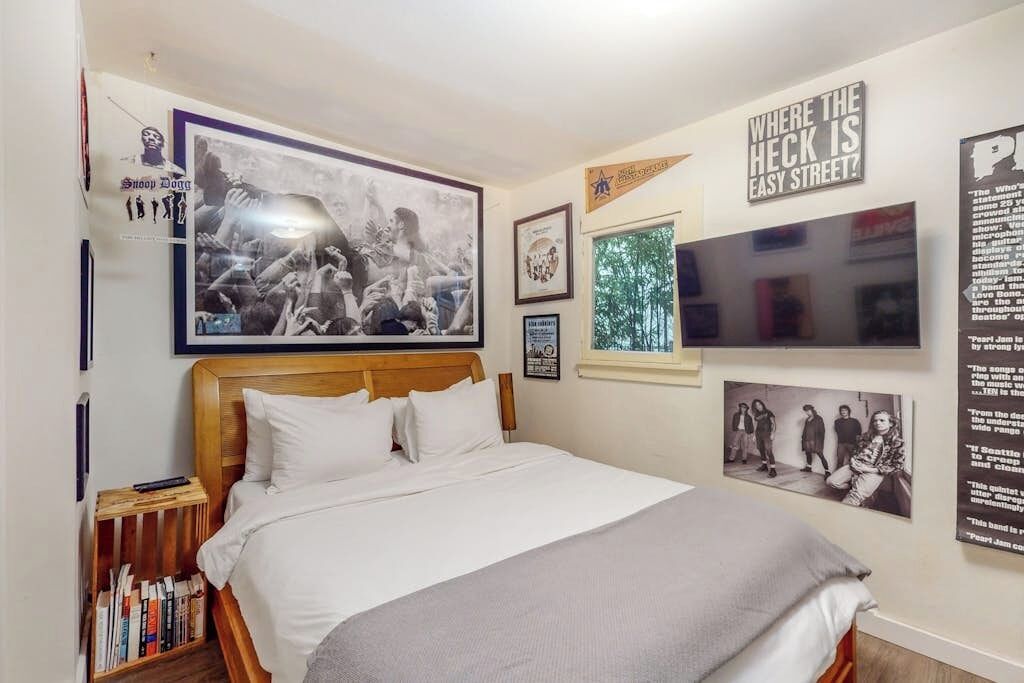 Un dormitorio con una cama, una estantería y varios carteles en las paredes.