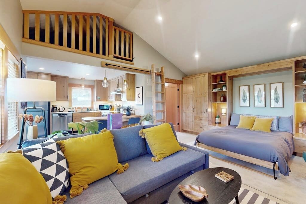 A modern interior with a sofa, bed, and dining area.