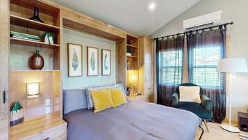 Een slaapkamer met een groot bed, houten planken, een bureau, een stoel en een raam met gordijnen.