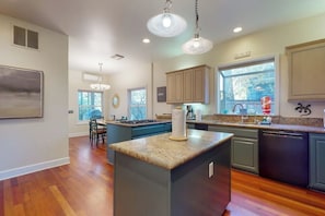 A spacious kitchen with a central island, wooden flooring, and pendant lighting. - Elegant 3BR Dog Friendly - Patio - Pool Table (Seattle)