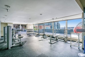 A gym with various exercise equipment, large windows, and a view of the city. - 2BR modern home with amazing views, pool & hot tub (Seattle)