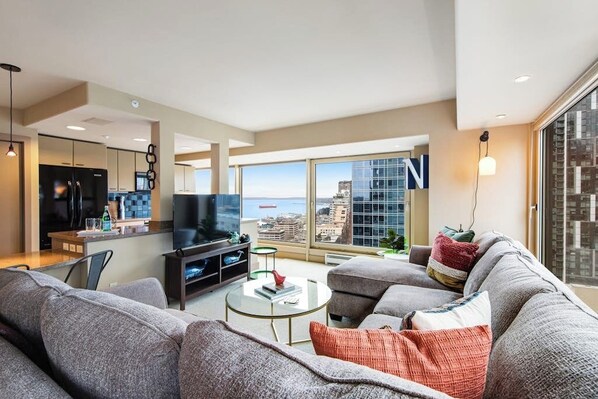 Un salon moderne avec un grand canapé, une table basse et un téléviseur à écran plat.