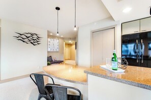 Une cuisine moderne avec un plan de travail en granit, un réfrigérateur et une horloge murale.