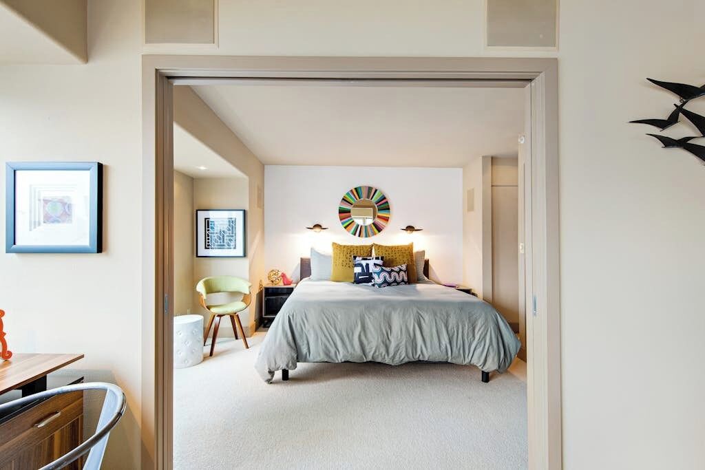 A bedroom with a bed, a wall clock, and a framed picture.