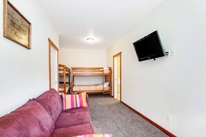 A room with a bunk bed, a sofa, and a mounted TV. - Custom 3BR - Balcony - Washer Dryer (Ronald)