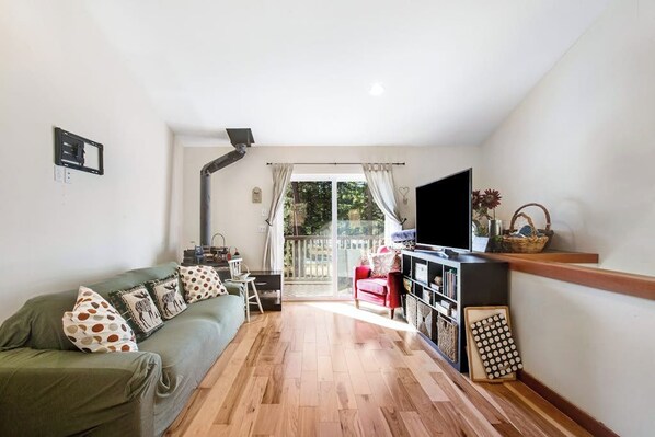 A living room with a sofa, TV, and a sliding door leading to a balcony. - Custom 3BR - Balcony - Washer Dryer (Ronald)