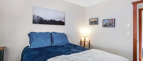 A bedroom with a bed, a nightstand, and wall art.