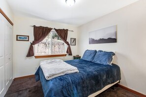 A bedroom with a bed, a window with curtains, a framed picture on the wall, and a carpeted floor. - Custom 3BR - Balcony - Washer Dryer (Ronald)