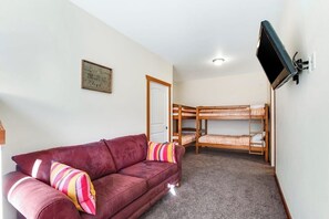 A room with a red sofa, bunk beds, a television mounted on the wall, and a framed quote on the wall. - Custom 3BR - Balcony - Washer Dryer (Ronald)